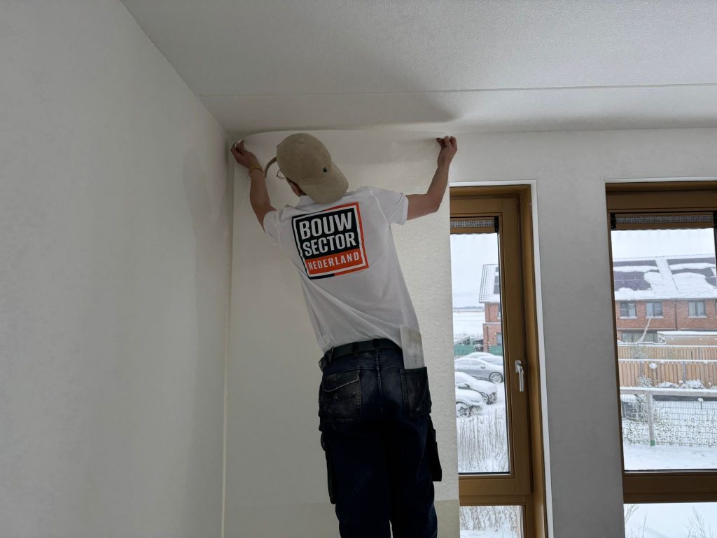Behanger van Bouwsector Nederland zet een baan glasvlies tot tegen het plafond van een nieuwbouwwoning