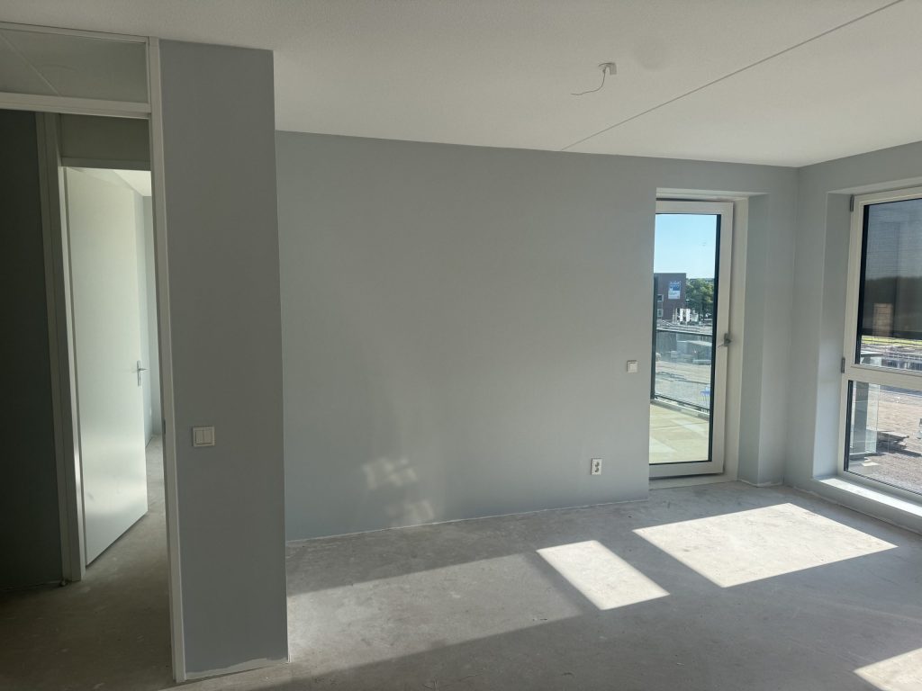 Lege nieuwbouwkamer met kale wanden en een betonvloer, klaar voor het glasvlies