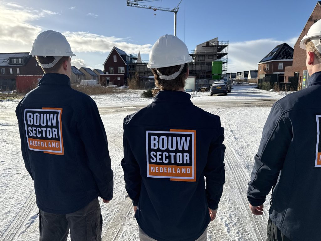 Drie vakmensen van Bouwsector Nederland met witte helm voor woningen in aanbouw en een bouwkraan
